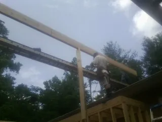 Carpenter setting a ridge beam over a new addition frame — Ice Dam Removal by Roofing Brothers in Prides Crossing