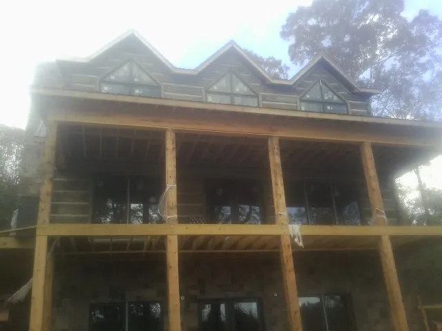 Dormers and porch framing on a large log home under construction — Roof Coating work by our crew in Prides Crossing