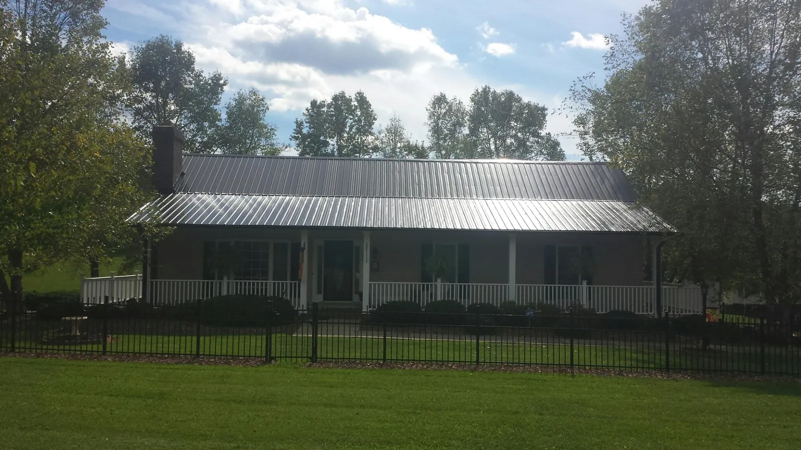 Gray metal roof on a brick ranch with a full width front porch — Gutter Guard Installation work by our crew in Prides Crossing