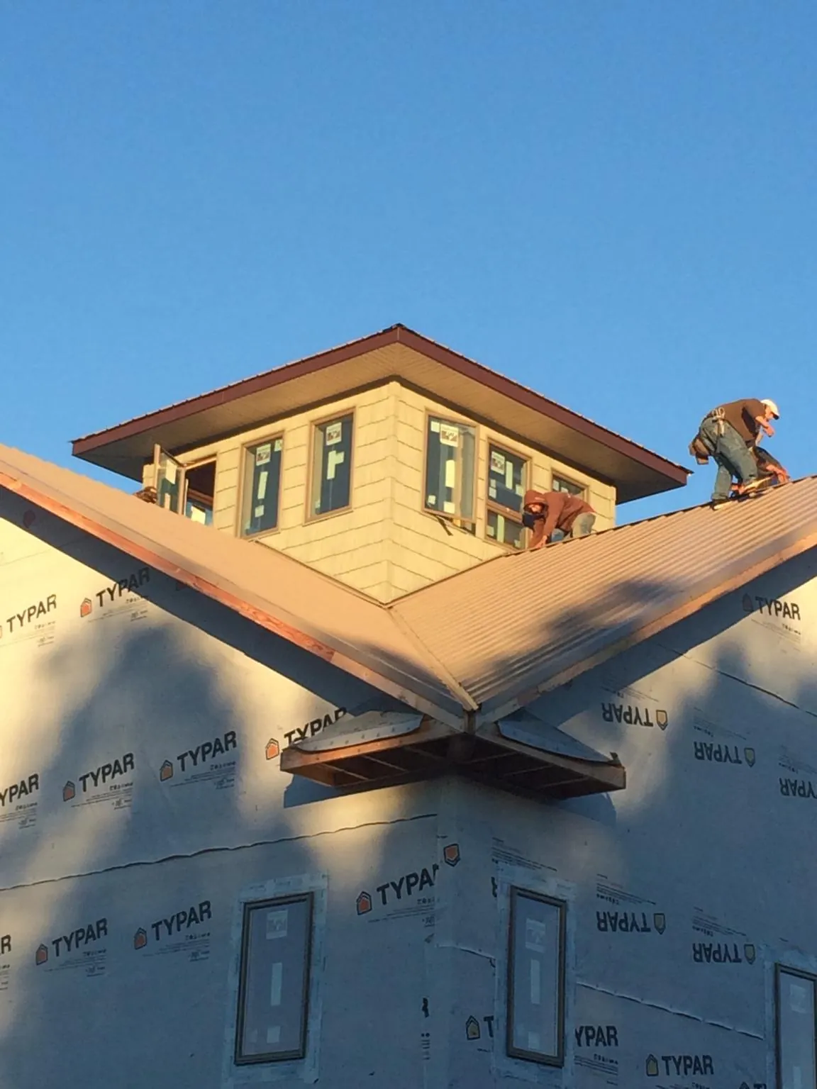 Roofers working around a rooftop cupola on a new metal roof at sunset — Roof Waterproofing in Prides Crossing by Roofing Brothers